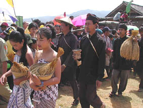 かごに入れたり竹筒に吊した稲束、儀式に使う道具を運ぶ人々