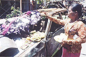 爆風を受け、大破した乗用車に祈りを捧げる女性